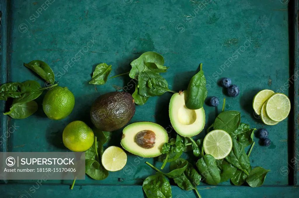Spinach leaves, avocados and blueberries on green ground