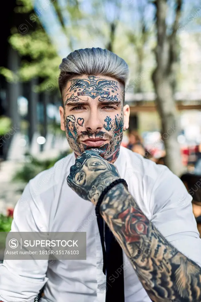 Young businessman with tattooed face, looking at camera