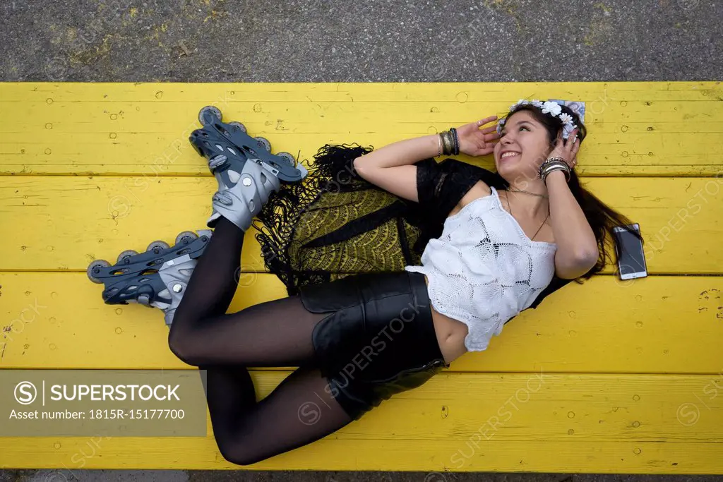 Smiling woman with inline skates lying on yellow table