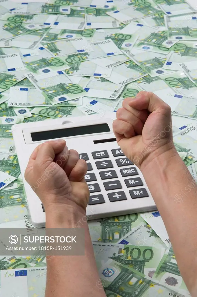 Man making fist over calculator on 100 euro notes