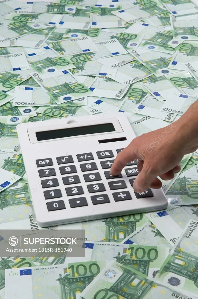 Man pressing calculator key on 100 euro notes