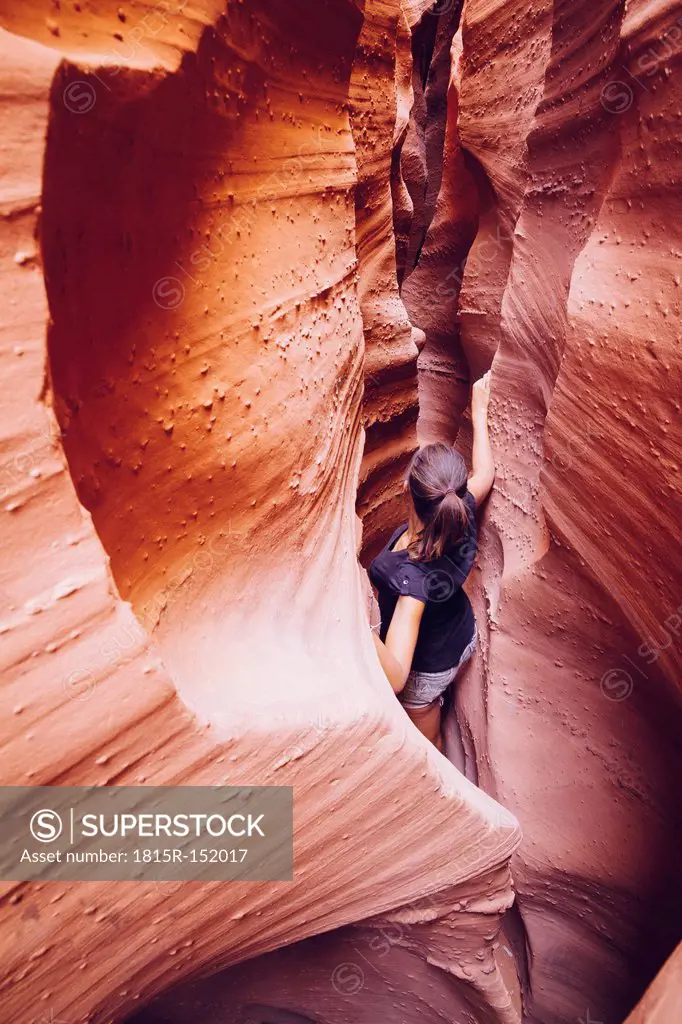 USA, Utah, Escalante, Peek-A-Boo and Spooky Slot Canyons, young woman climbing in gorge