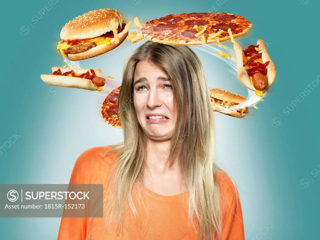 Disgusted young woman with flying fast food around her head, Composite