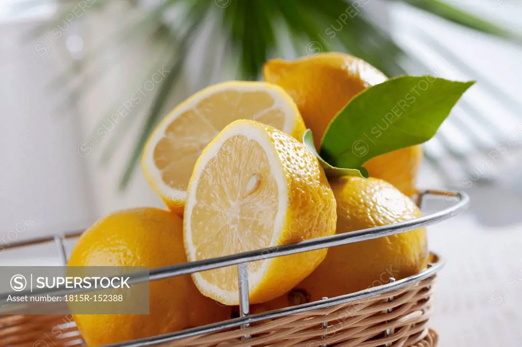 Sliced and whole lemons in basket, studio shot