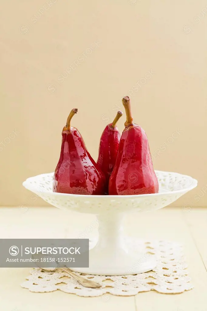 Poached pears in red wine on cake stand