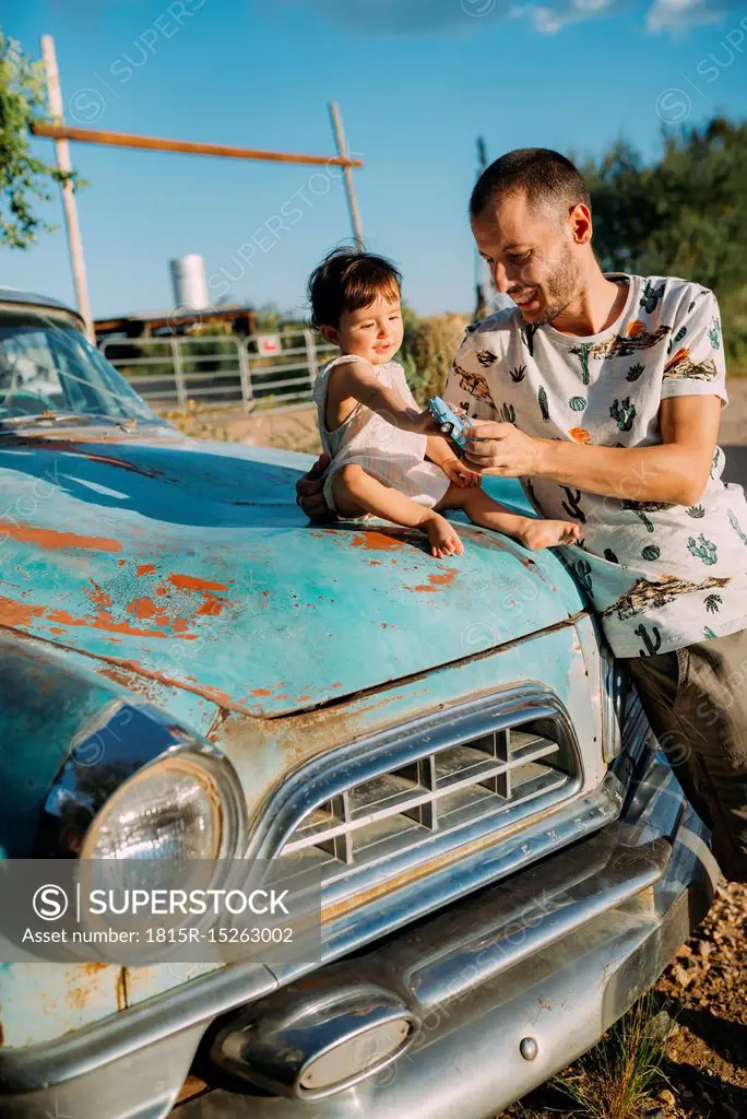 USA, Arizona, Father and baby playing with a reproduction of an old vintage car, at Route 66