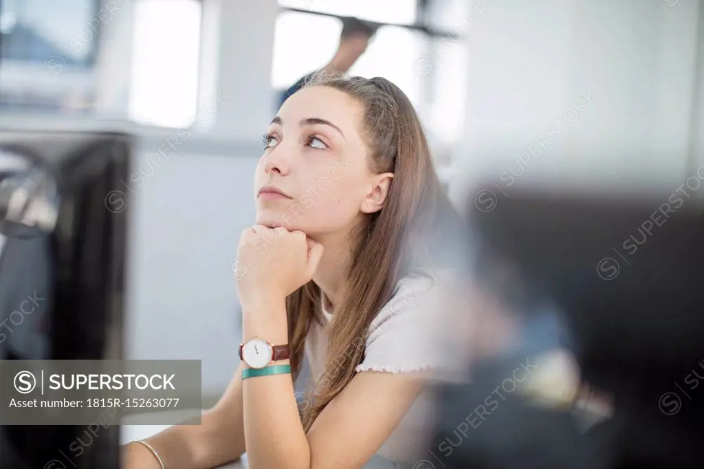 Teenage girl day dreaming in computer class