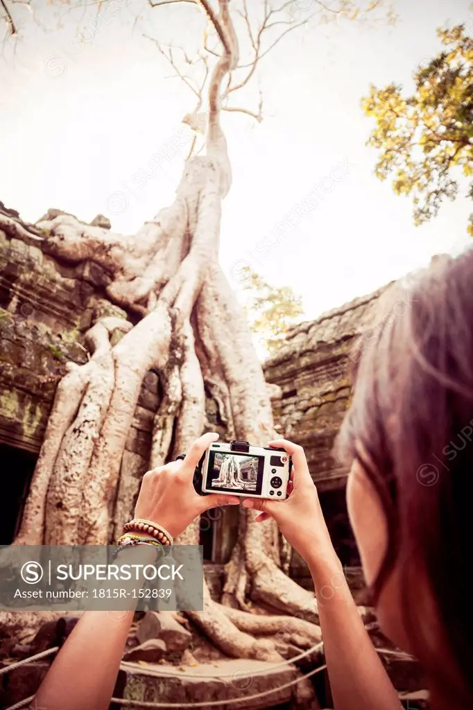 Cambodia, Angkor Wat, Woman takes pictures of the famous tree in Ta Prohm Temple