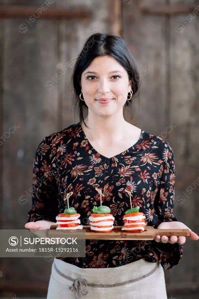 Portrait of smiling woman serving Caprese Salad