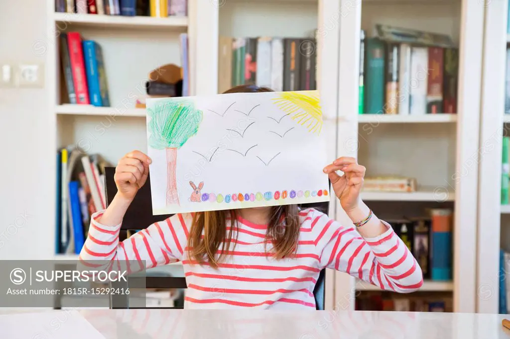 Little girl hiding her face behind her Easter bunny painting