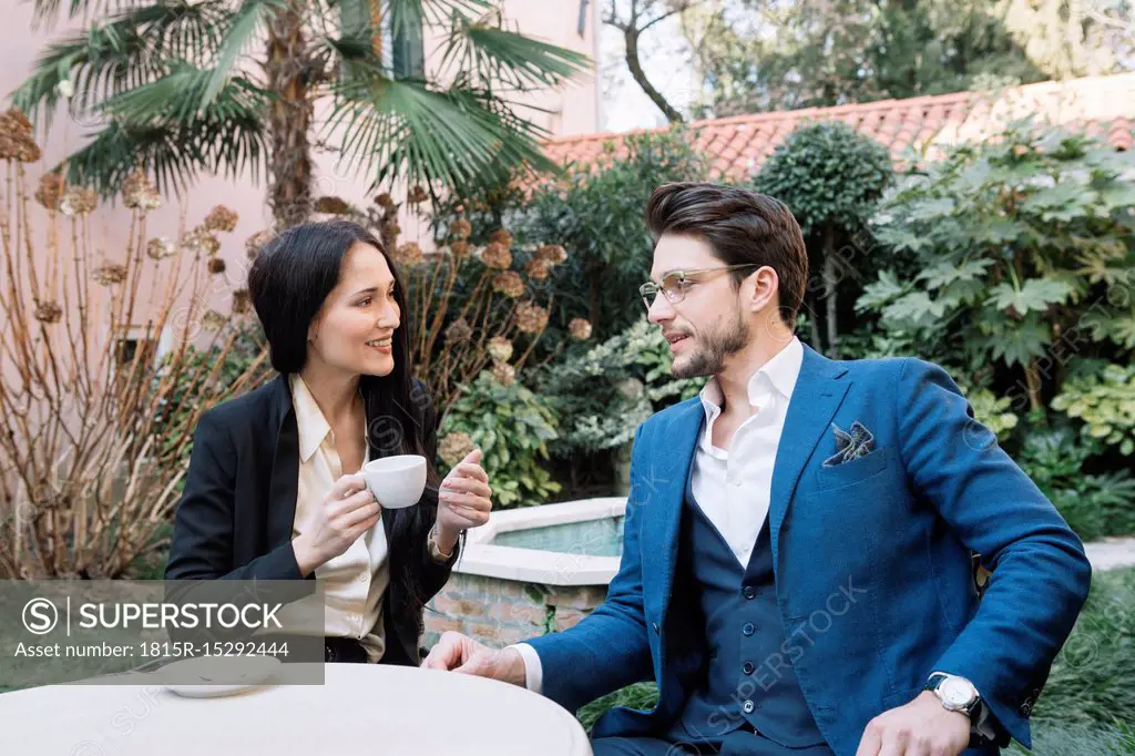 Elegant couple talking in a garden cafe
