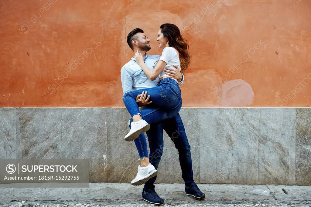 Carefree couple in love in front of a wall outdoors