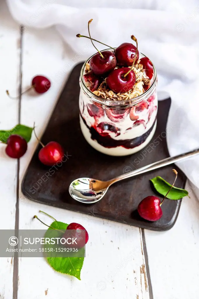 Glass of natural yoghurt with cherries, cherry jam and granola