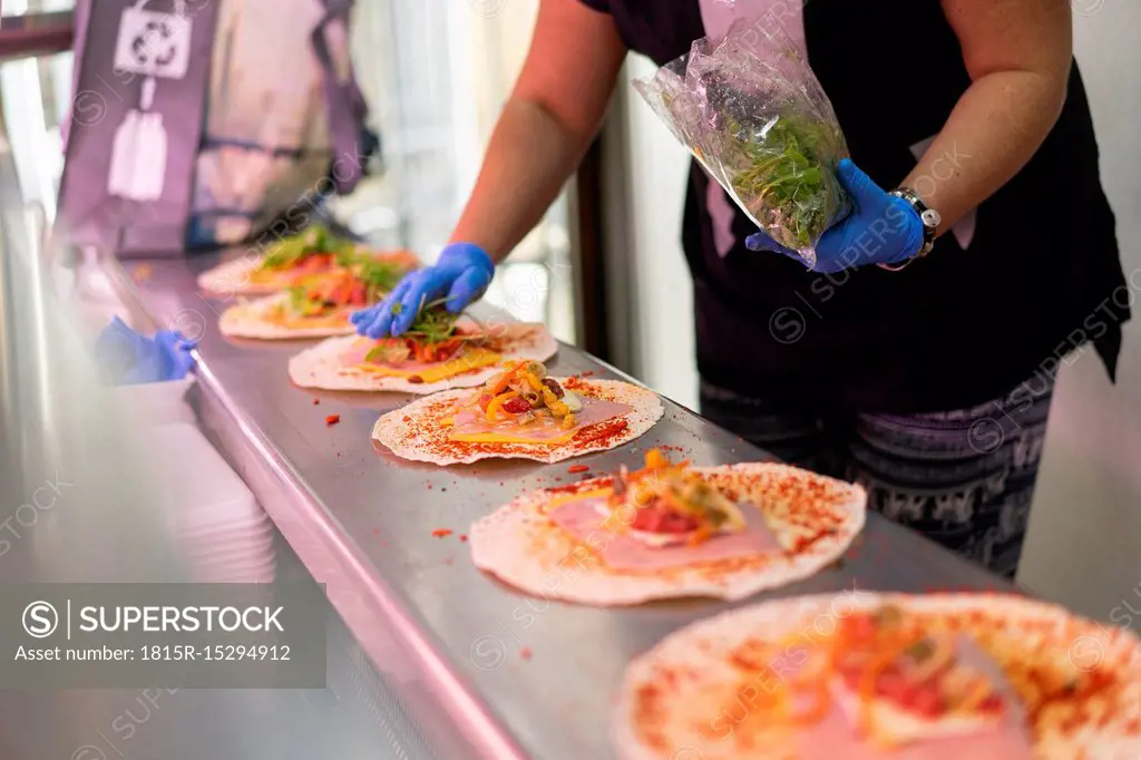 Woman in market stall filling tortilla wraps