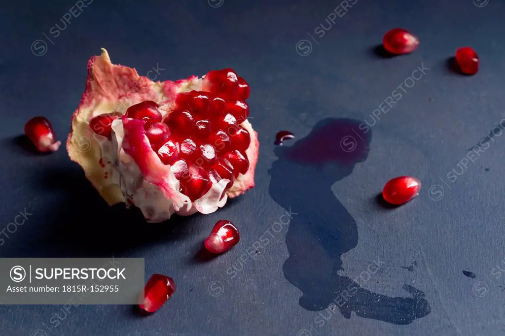 Pits and piece of pomegranate Punica granatum on blue wood, close-up