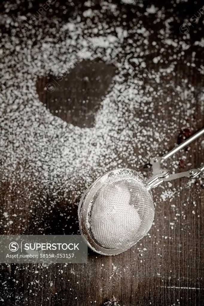 Tea strainer filled with icing sugar and imprint of cookie