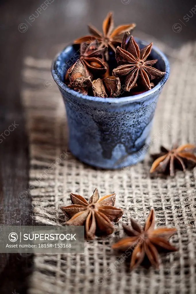 Star anise in tiny blue cup on burlap, studio shot