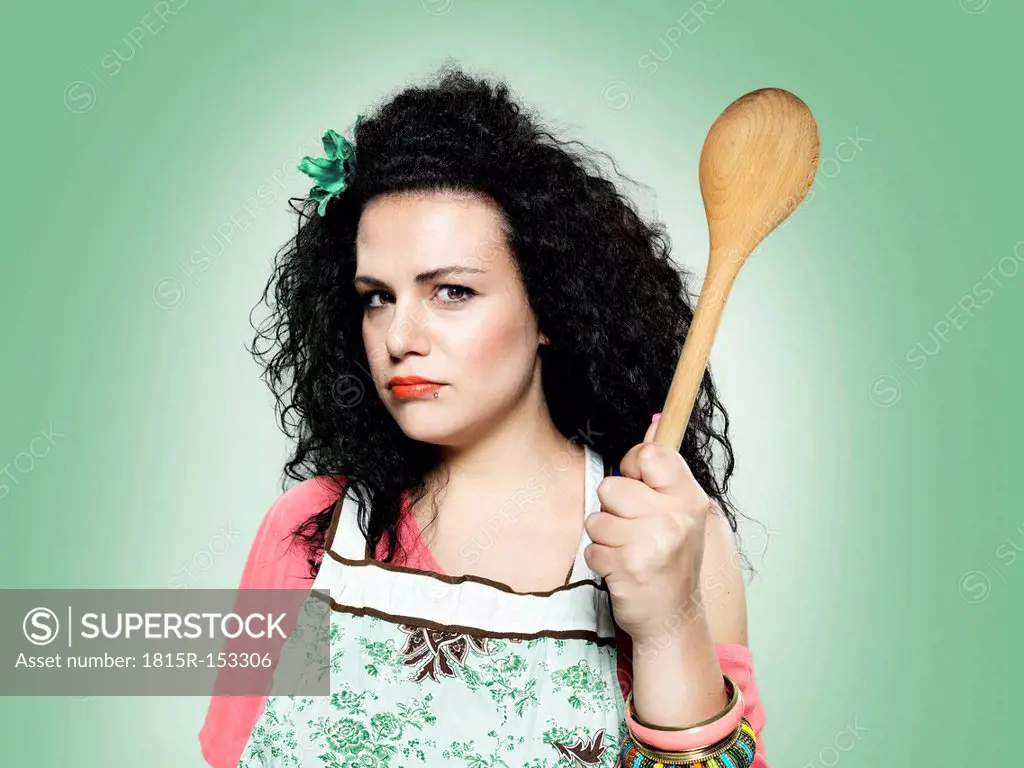 Portrait of young woman holding wooden spoon, studio shot