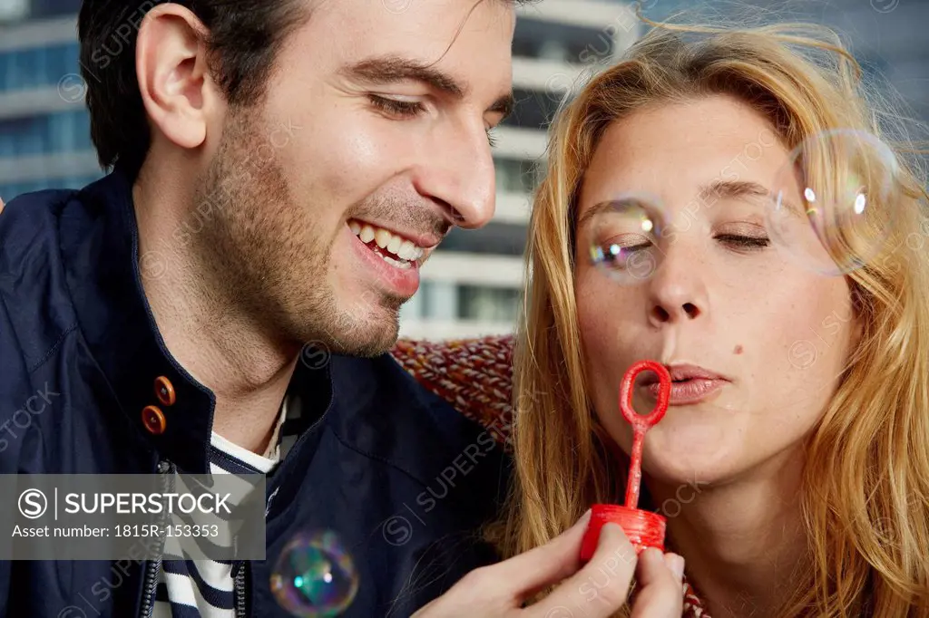 Germany, Dusseldorf, Young couple making soap bubbles