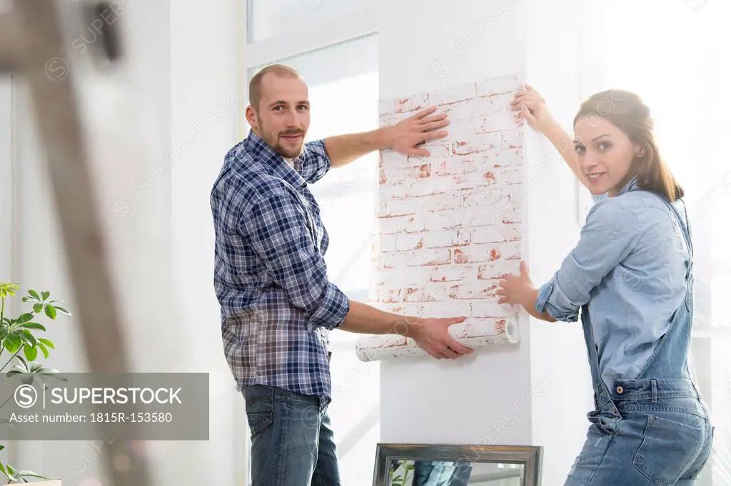 Young couple moving into new home, testing wallpaper