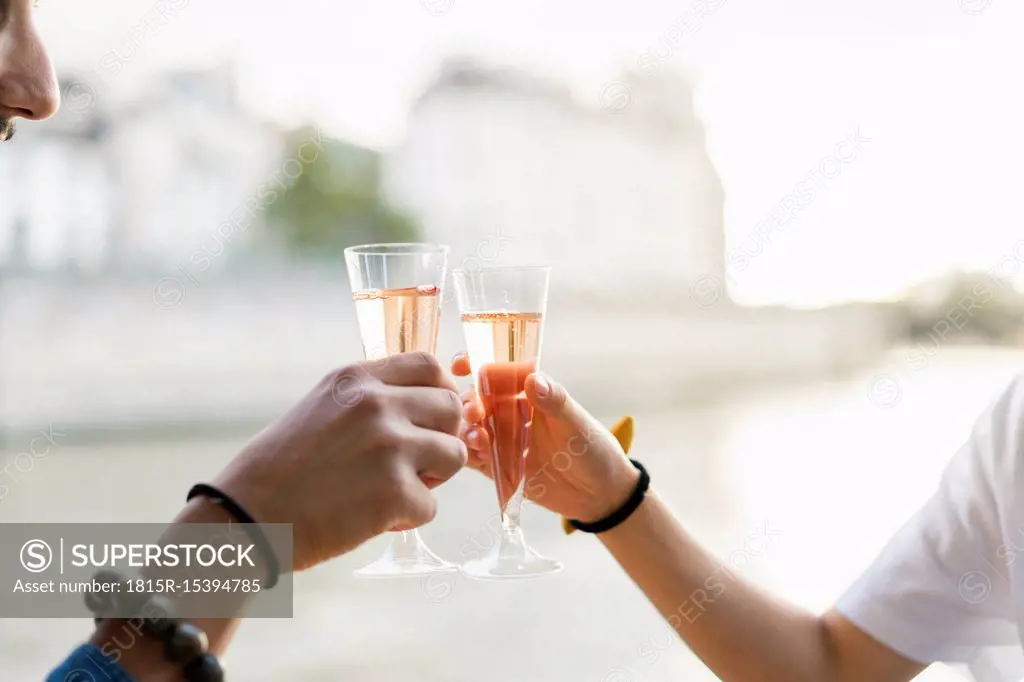 Close-up of couple clinking champagne glasses at the riverside