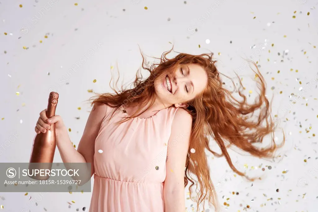 Portrait of happy young woman dancing with bottle of champagne