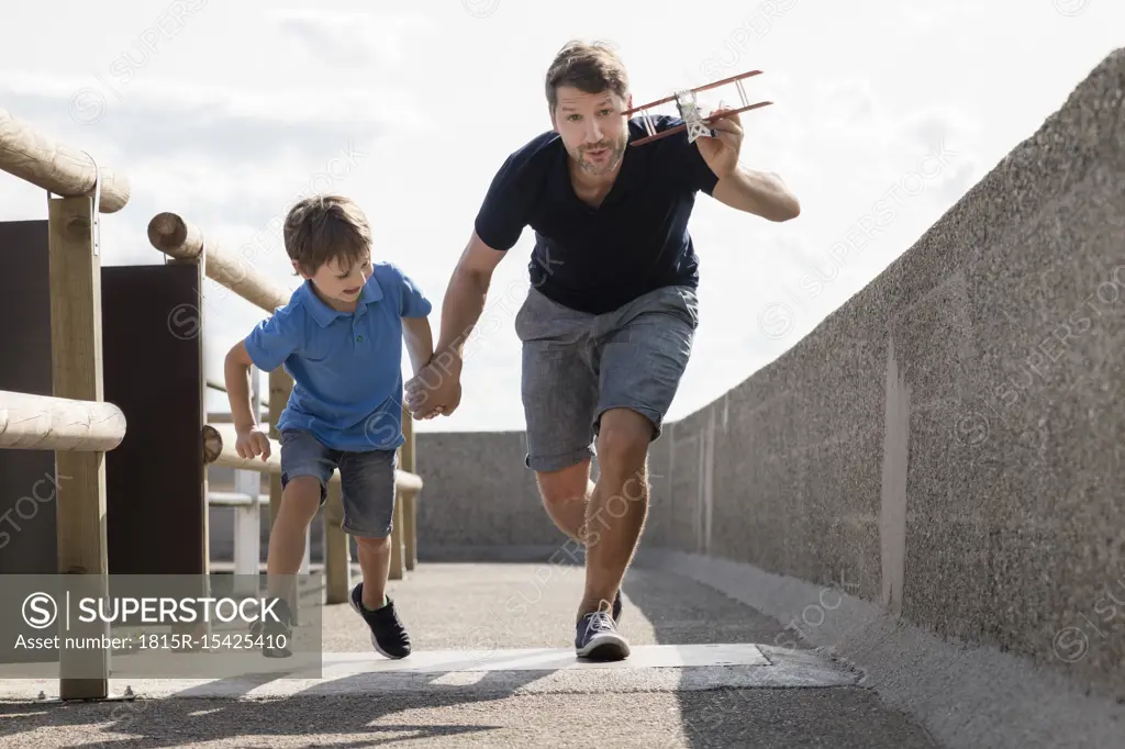 Father and son running with toy plane