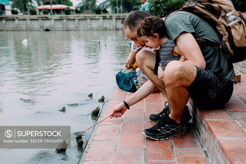 Thailand, Bangkok, Ayutthaya, father and daughter feeding turtles