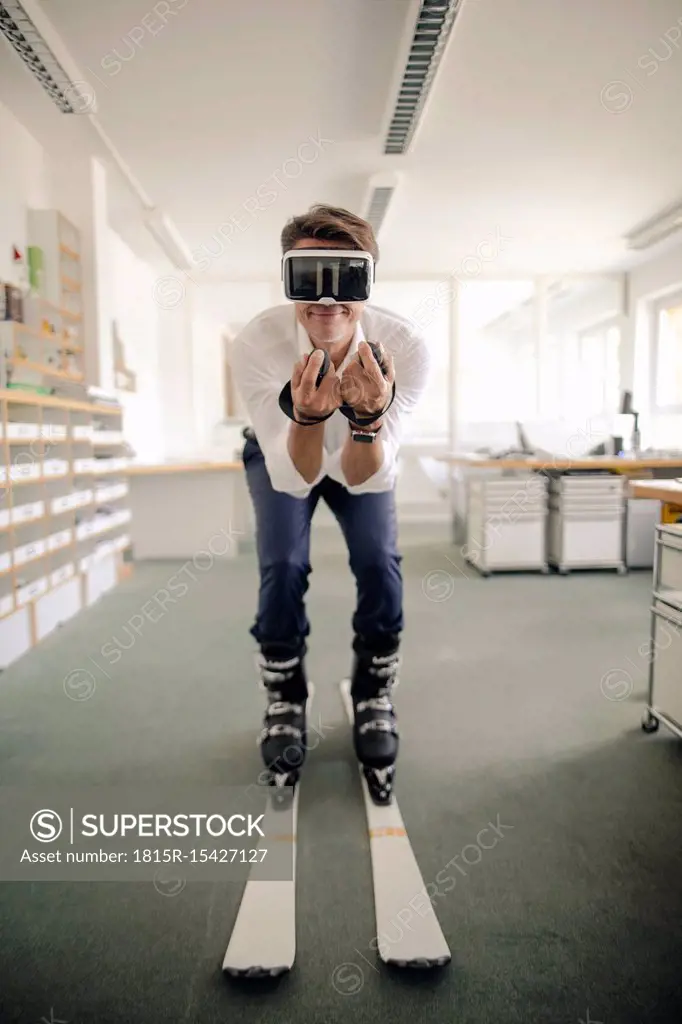Businessman skiing in office, using VR glasses