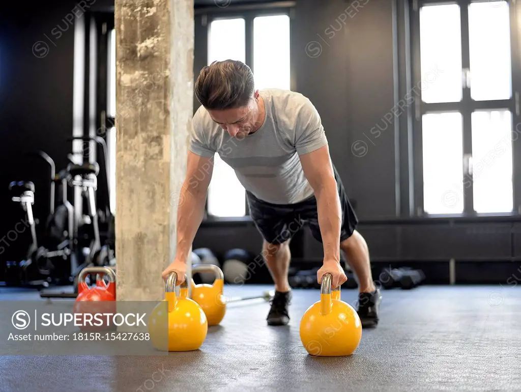 Man doing pushups on kettlebells at gym