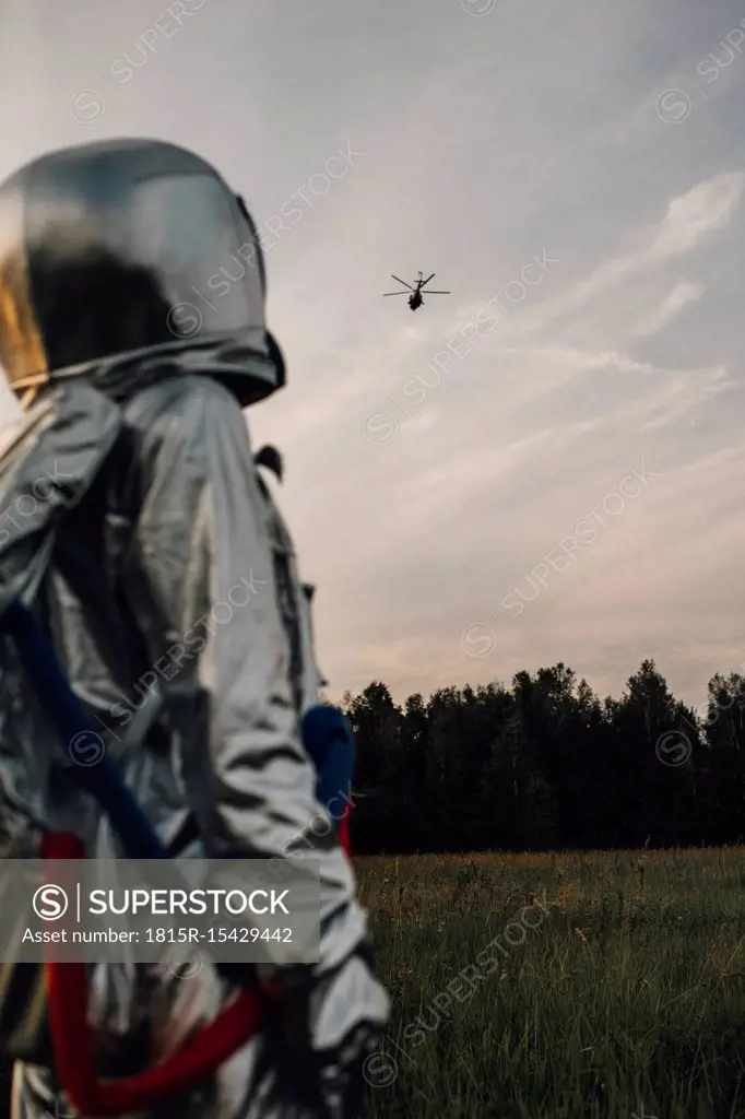 Spaceman exploring nature, watching helicopter