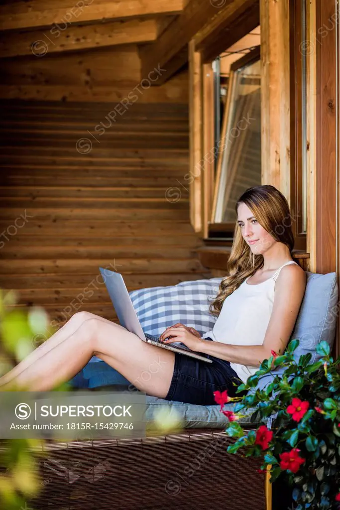 Woman relaxing on balcony using laptop