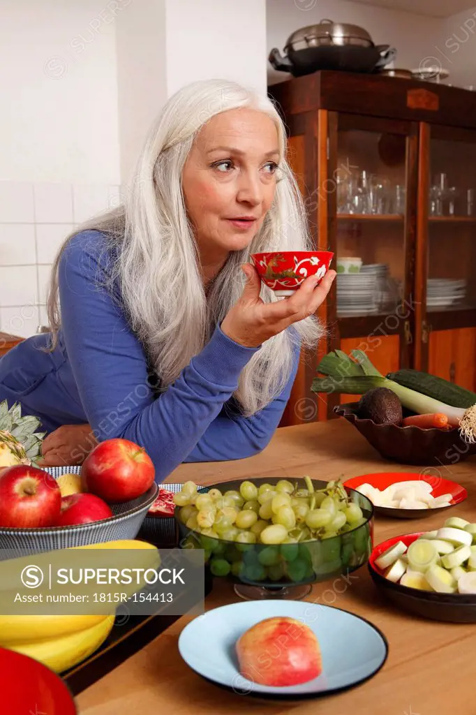 Germany, Dusseldorf, Senior woman with raw food drinking tea
