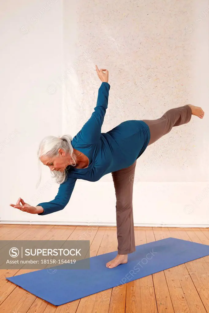 Germany, Dusseldorf, Senior woman practicing yoga