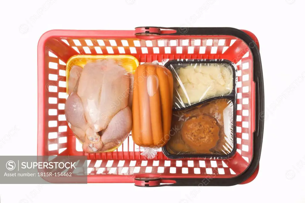 Shopping basket with convenience food, conserved sausages and a chicken in transparent plastic wrapping, studio shot