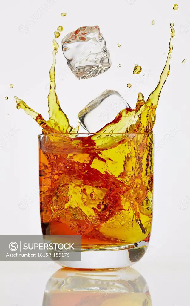 Ice cube splashing into glass of Whiskey