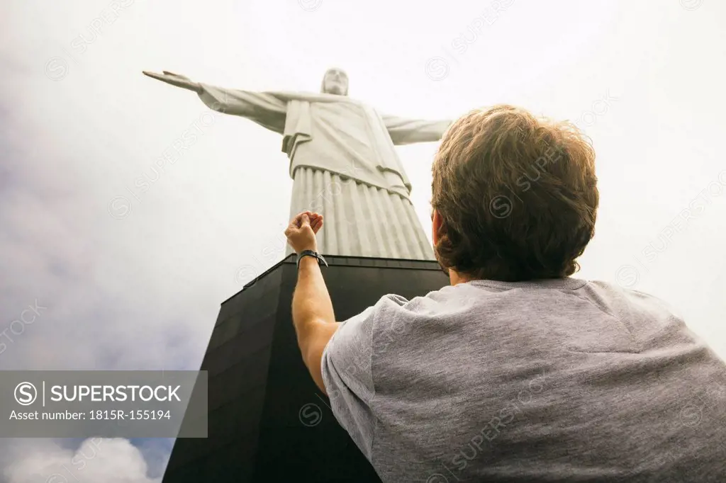 Brazil, Rio de Janeiro, Corcovado, Man praying at Jesus Christ the Redeemer statue