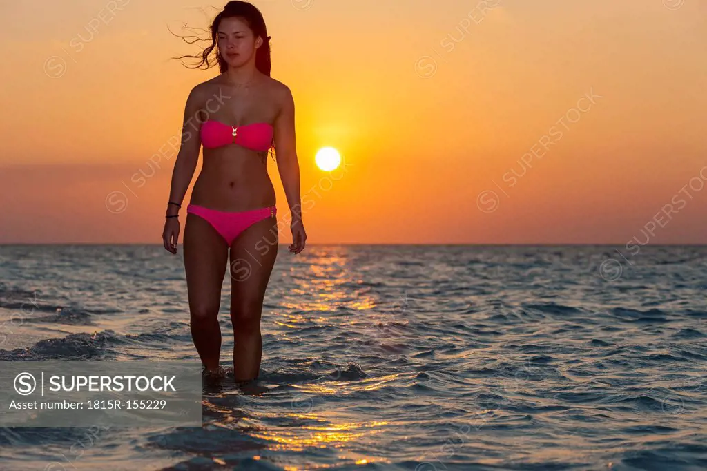 Maledives, young woman walking in water