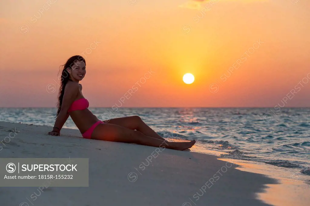 Maledives, young woman sitting at beach