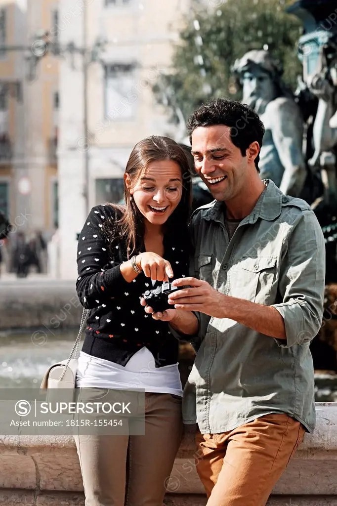 Portugal, Lisboa, Baixa, Rossio, Praca Dom Pedro IV, smiling young couple looking at own pictures