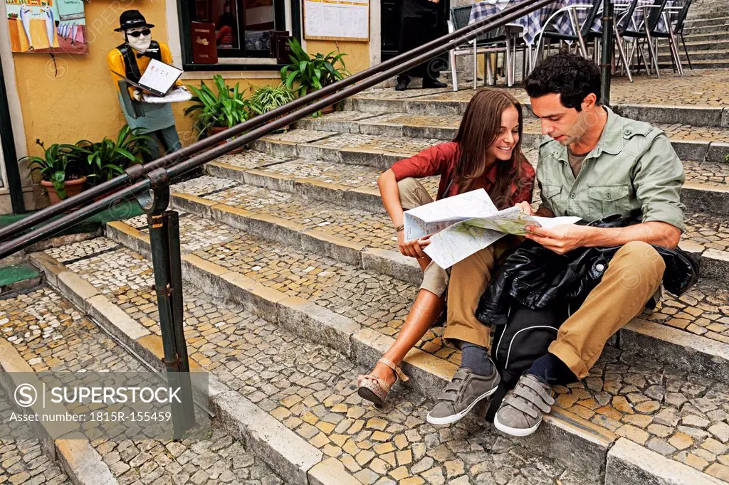 Portugal, Lisboa, Carmo, Calcada du Duque, young couple with city map sitting on stairs