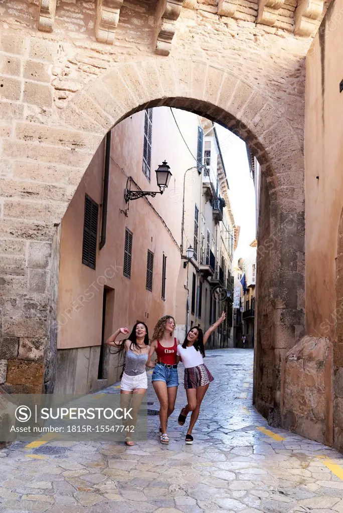 Spain, Mallorca, Palma, three happy young women exploring the city