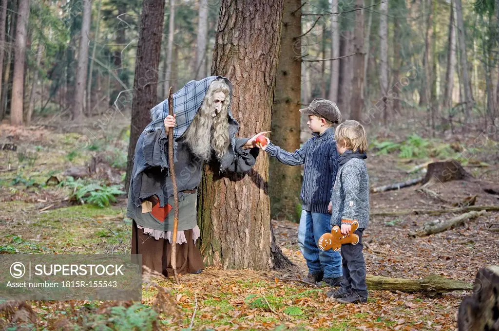 Germany, North Rhine-Westphalia, Moenchengladbach, Scene from fairy tale Hansel and Gretel, witch offering an apple to the children