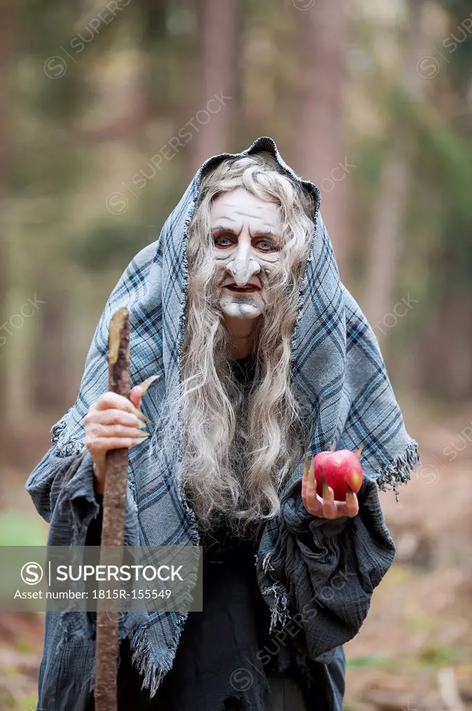 Germany, North Rhine-Westphalia, Moenchengladbach, Scene from fairy tale, witch holding an apple in the woods