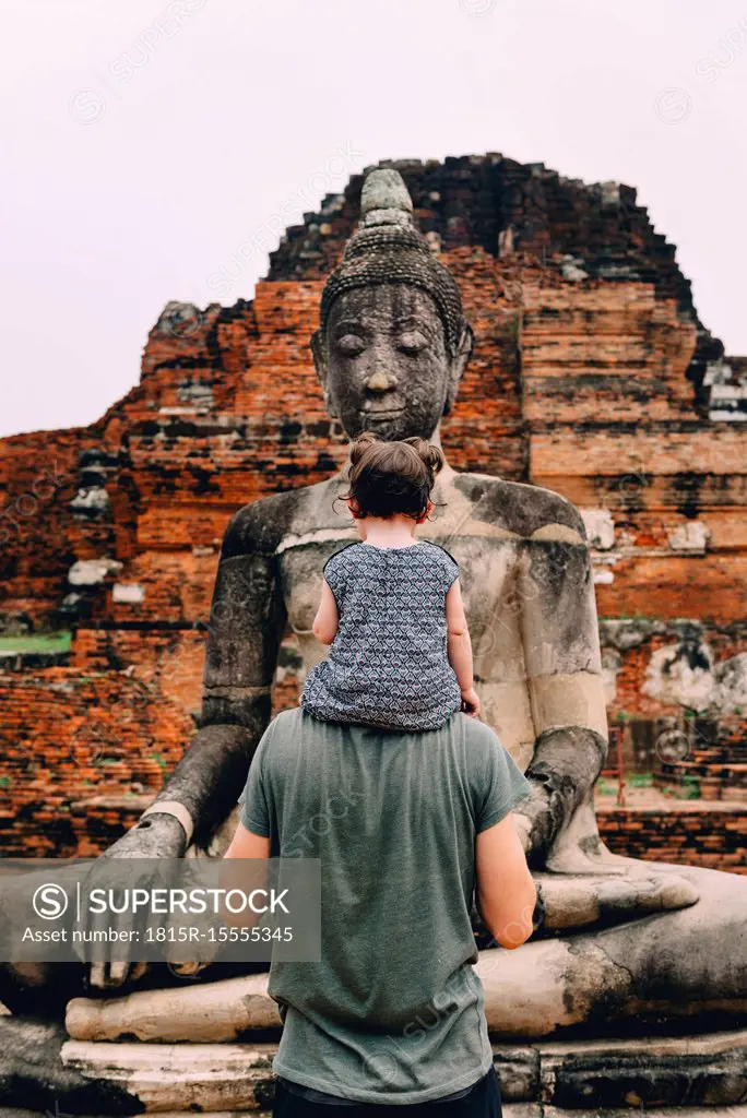 Thailand, Ayutthaya, Father and daughter looking at a Buddha statue at Wat Mahathat