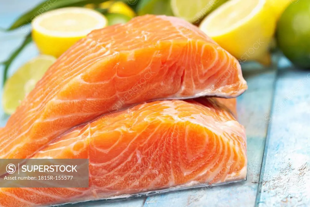 Salmon fillets (Salmo salar) and lemons on blue wooden table