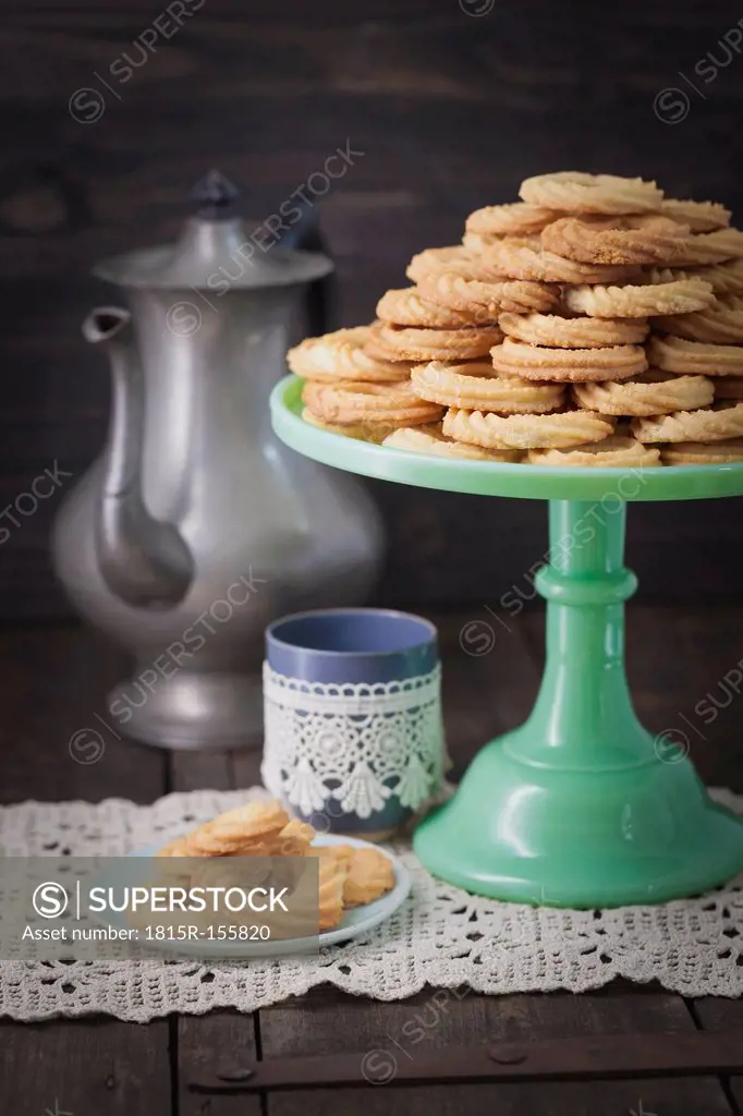 Traditional spritz cookies on green cake plate and coffeepot in background<br />