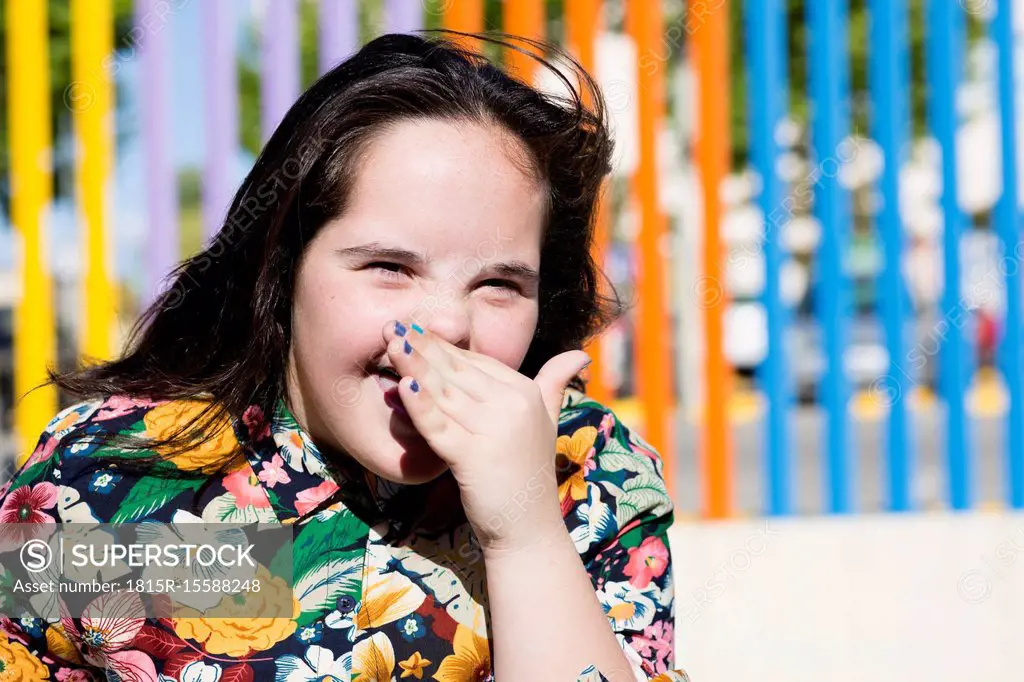 Teenager girl with down syndrome laughing, hand covering mouth