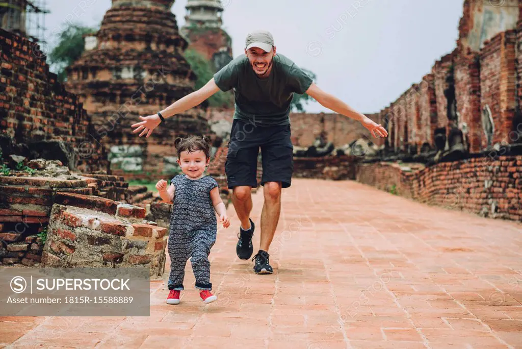 Thailand, Ayutthaya, Father and daughter running in the ancient ruins of a temple at Wat Mahathat