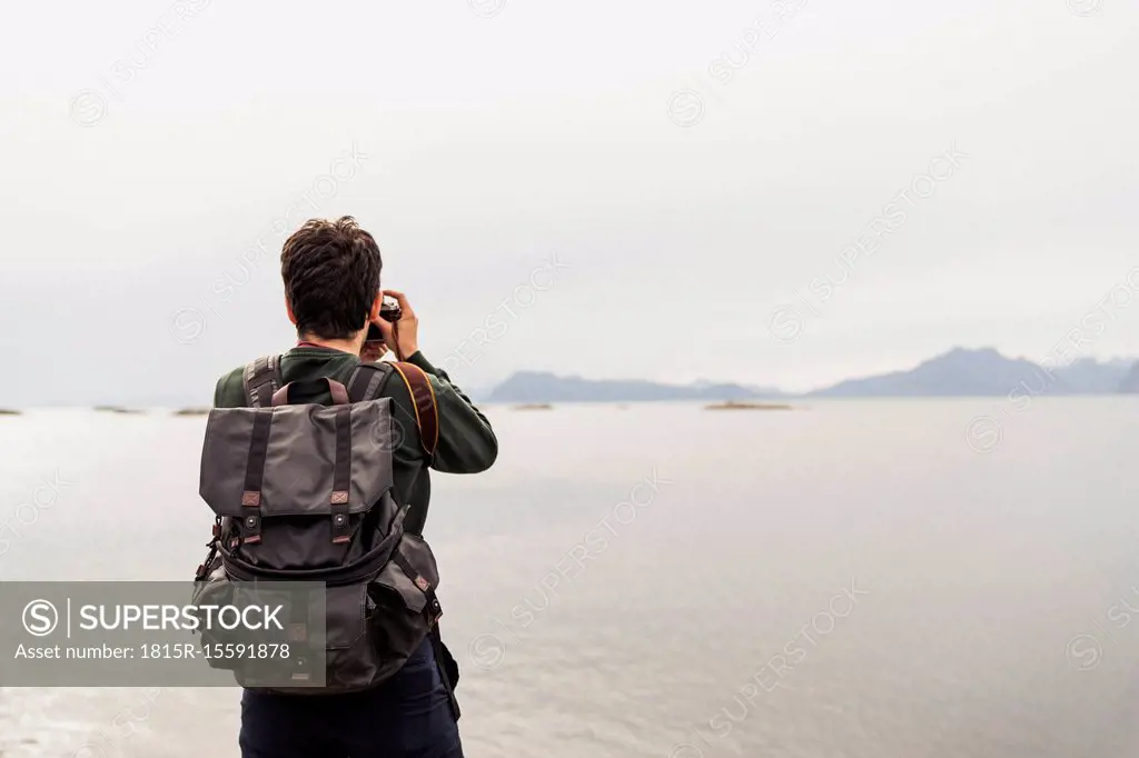 Young man taking pictures of a lake in Vesteralen Island, Lapland, Norway